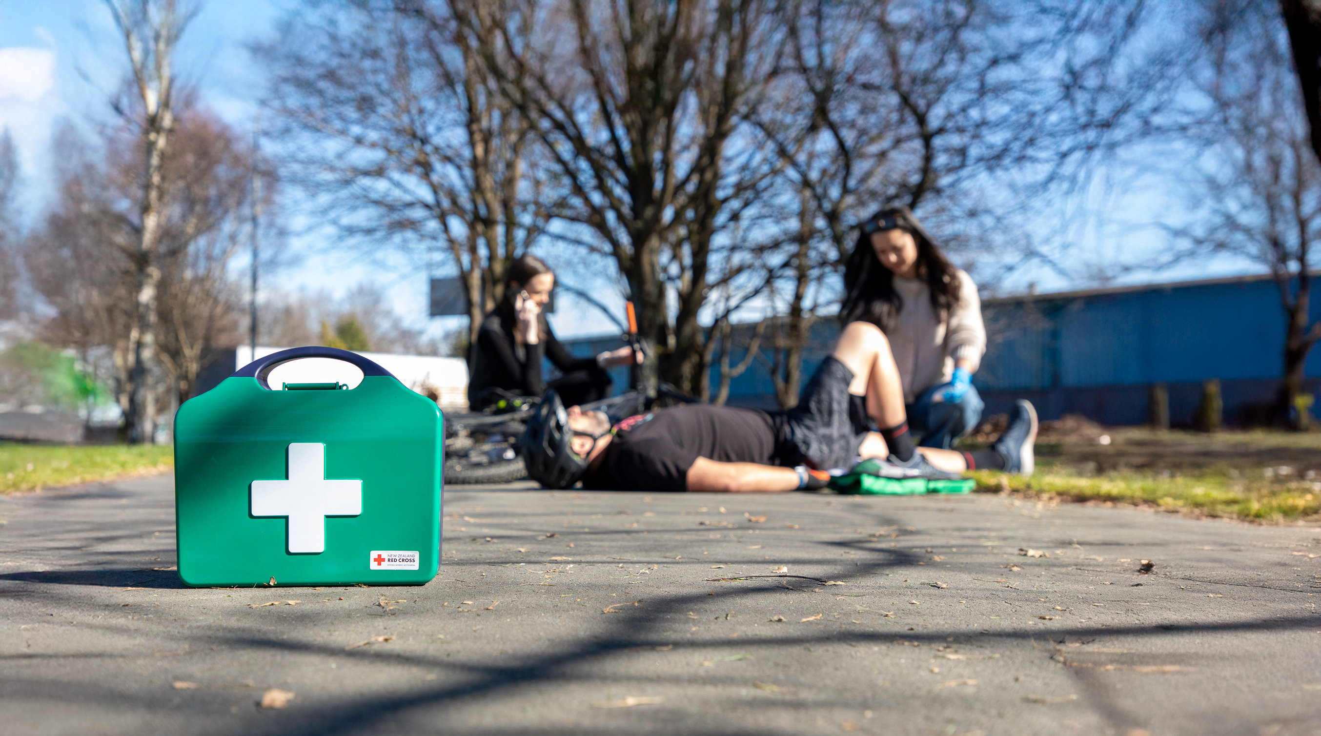 First aid kit on a wooden surface with people in the background