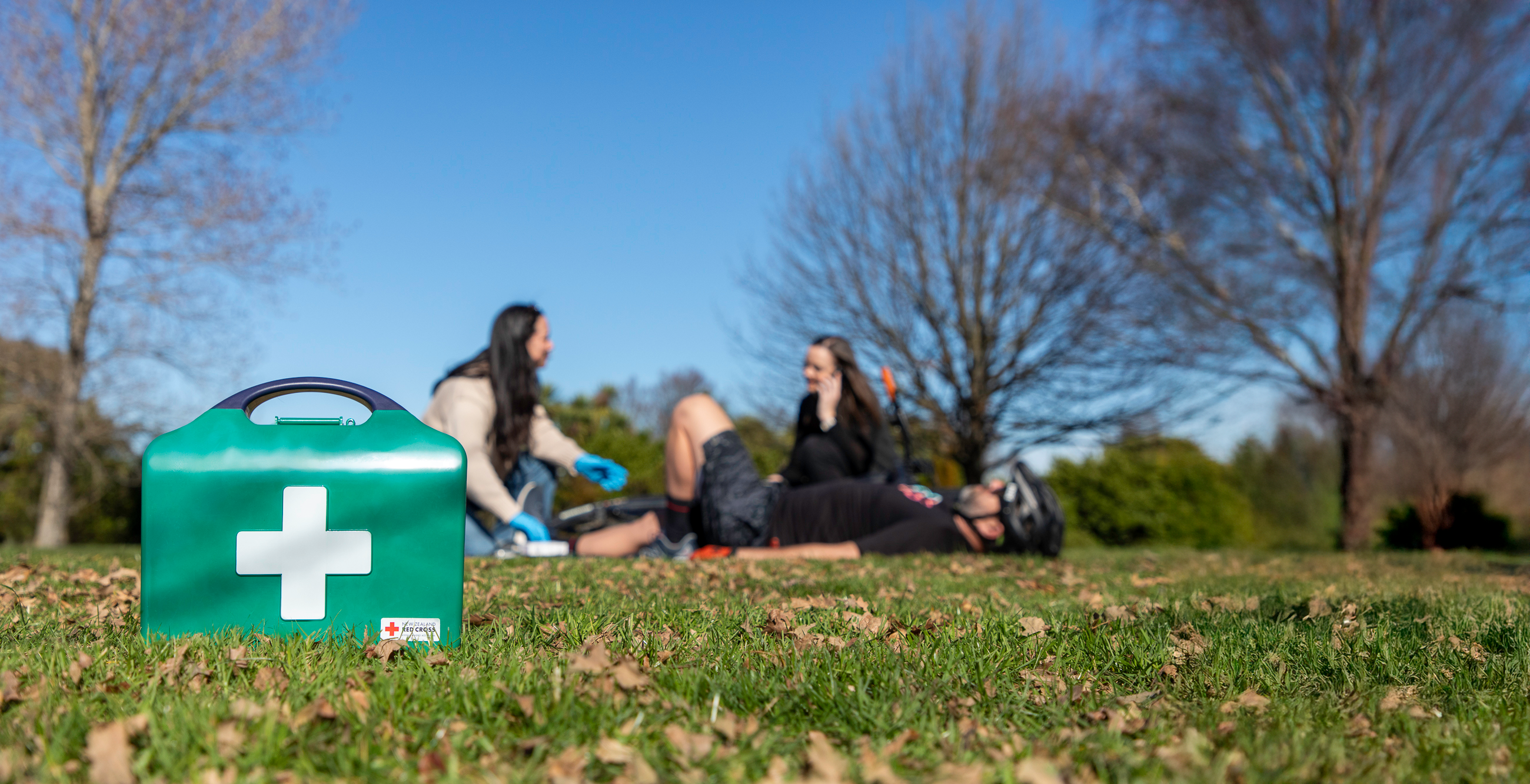 First aid kit on grass with people in the background