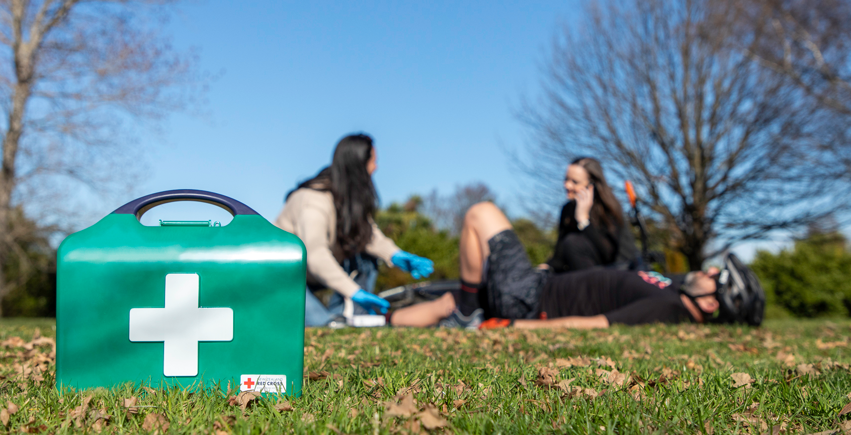 First aid kit on grass with people in the background